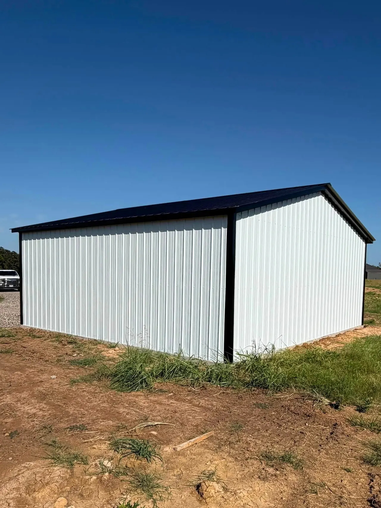 White metal building with a dark roof and blue sky