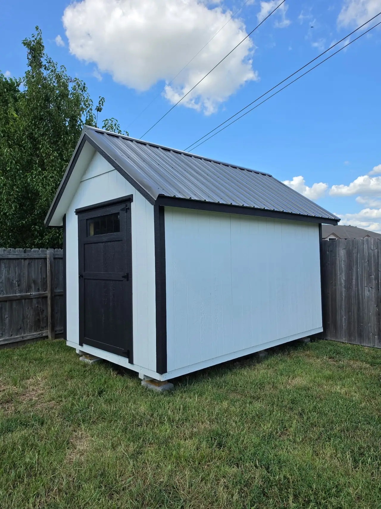 White portable building with a black door and a black metal roof