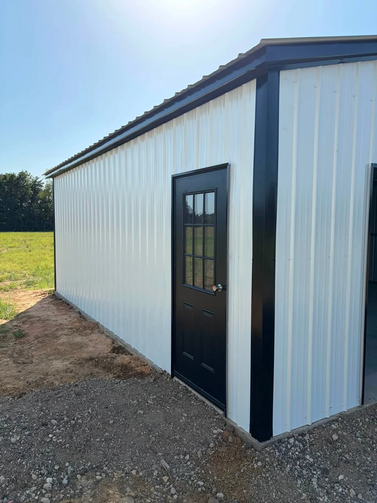 White metal building with a black entry door