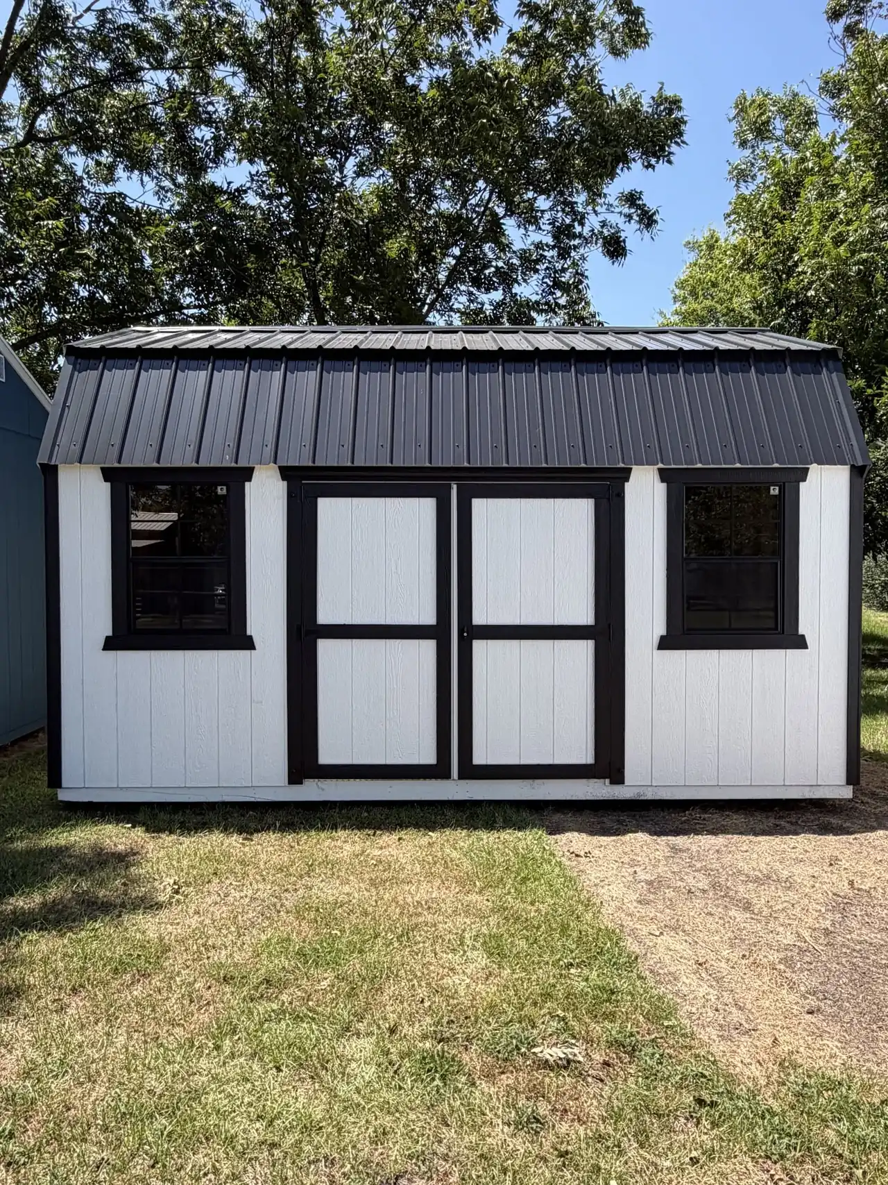 White portable building with black trim and double doors