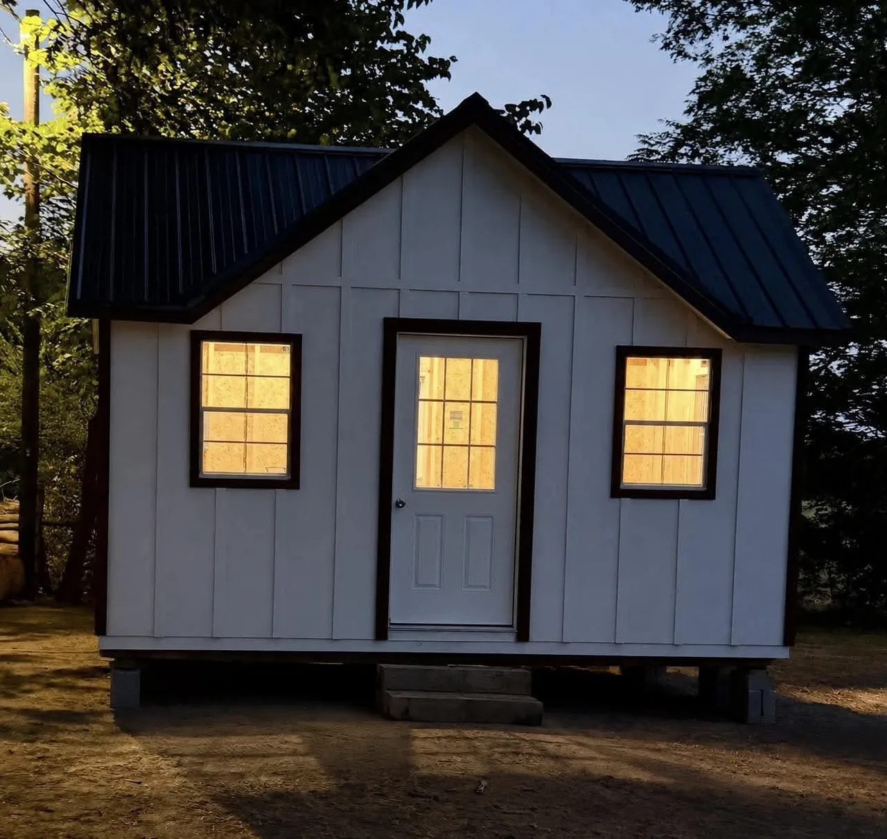 Gray cottage-style building with lit windows at dusk