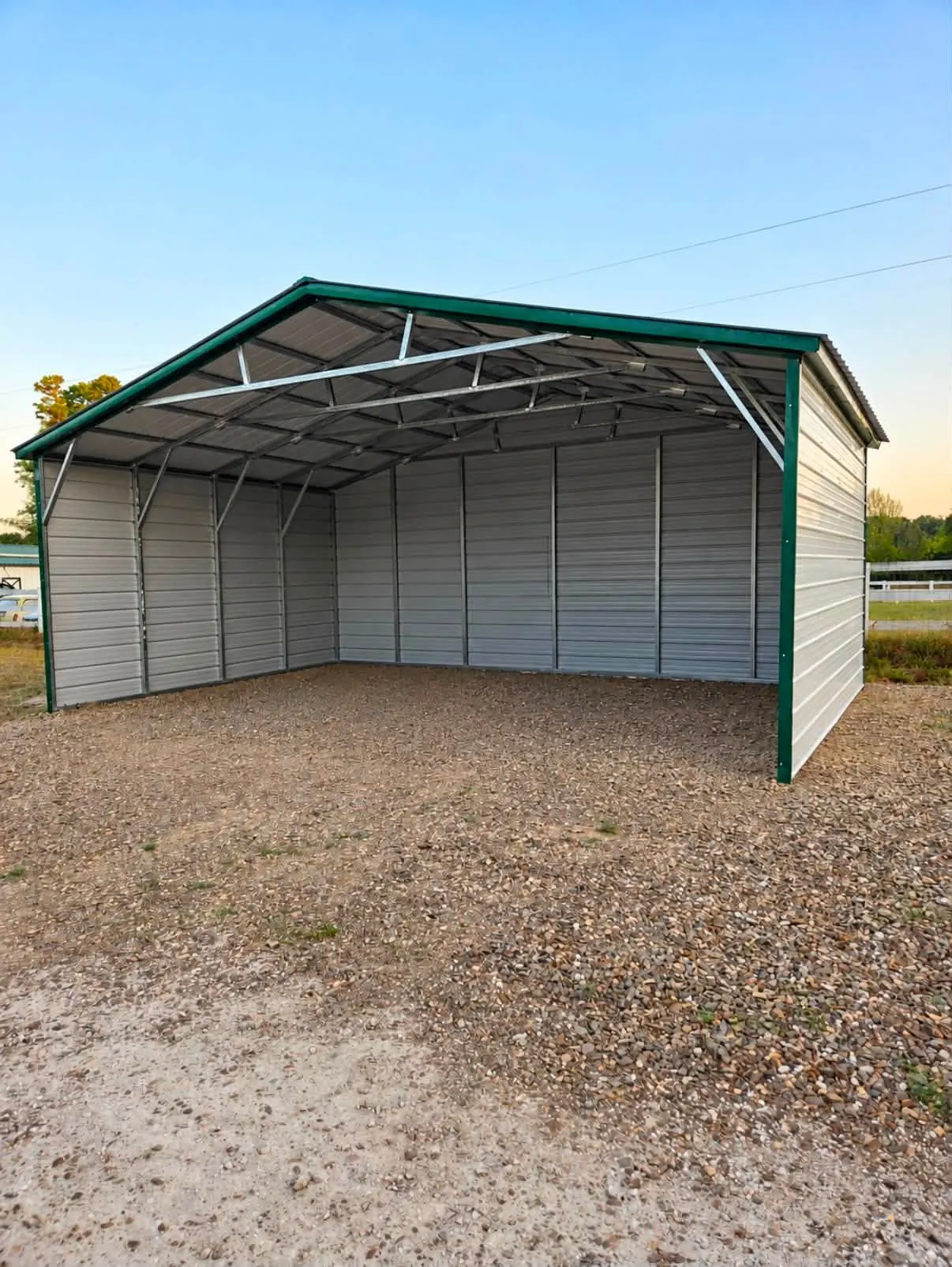 Open metal carport with a green roof on a gravel pad