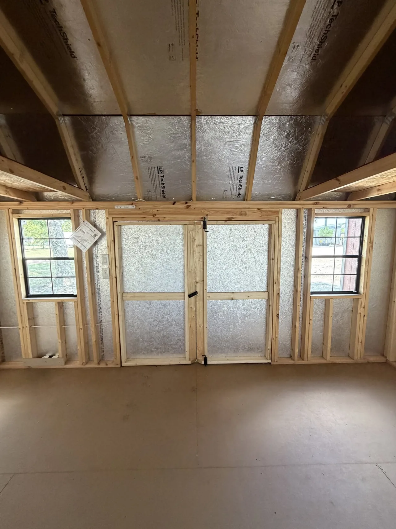 Inside a portable building with framed walls, windows and double doors